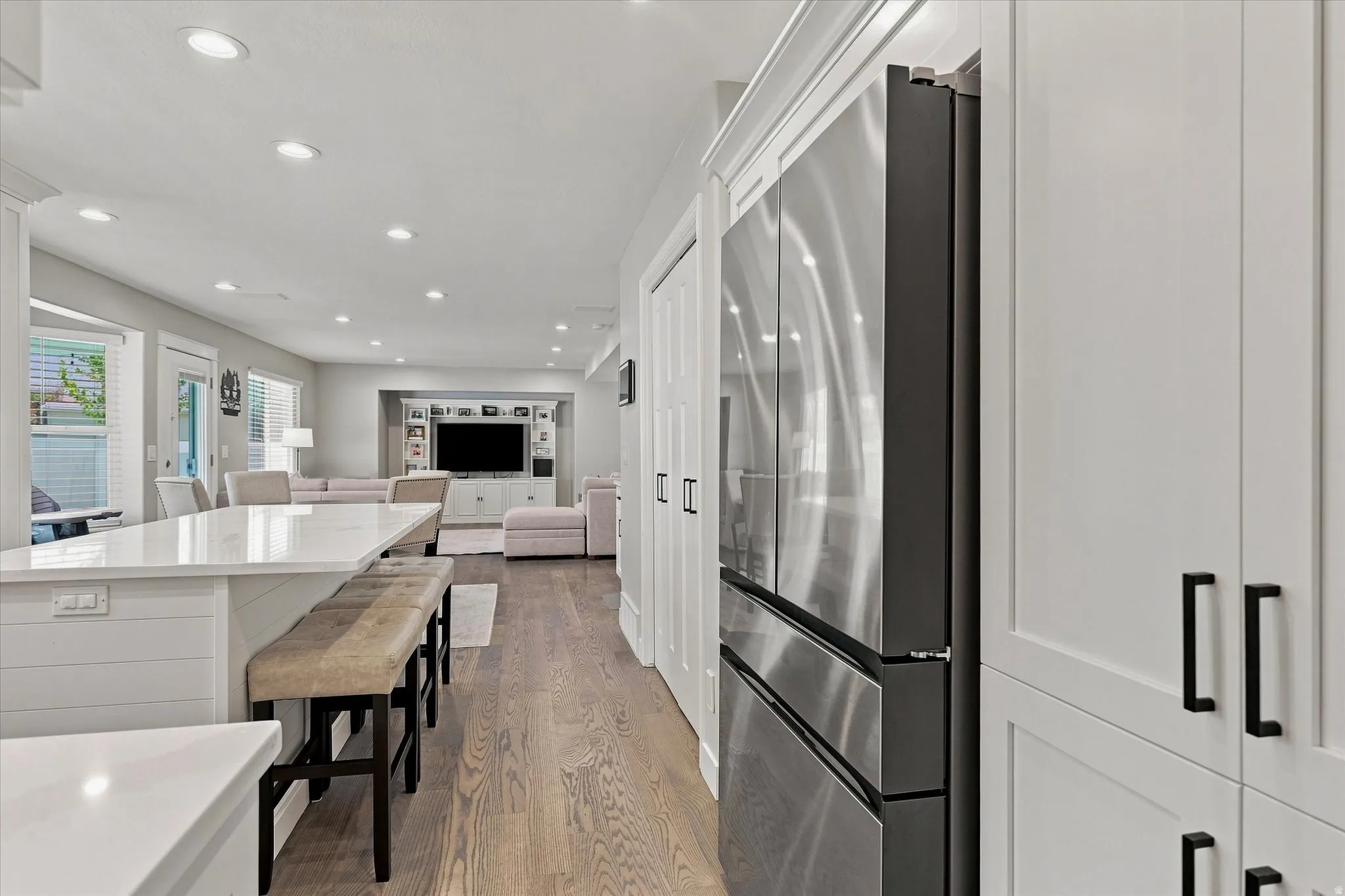 Open-concept living space featuring wood-finish flooring, recessed lighting, and a kitchen island with a light-toned countertop