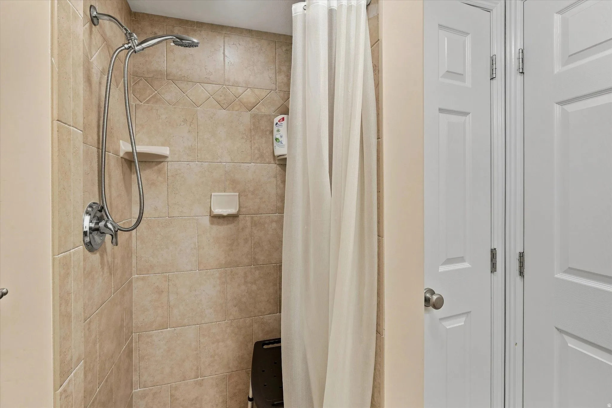 Tiled shower with handheld shower fixture and built-in shelving