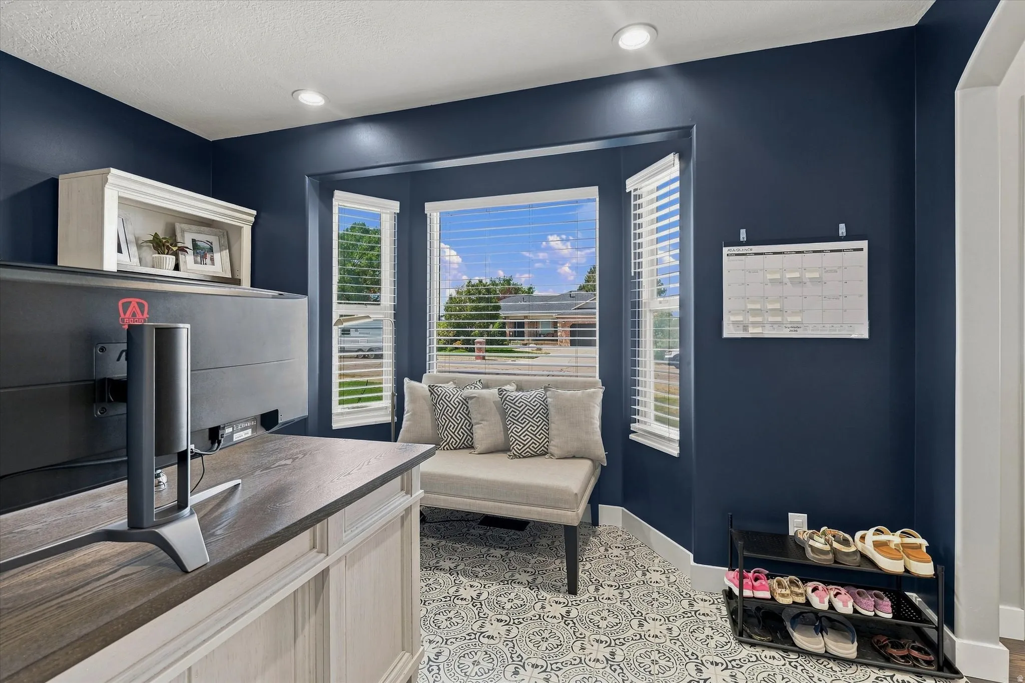 Recessed lighting illuminates the room, featuring a bay window with blinds