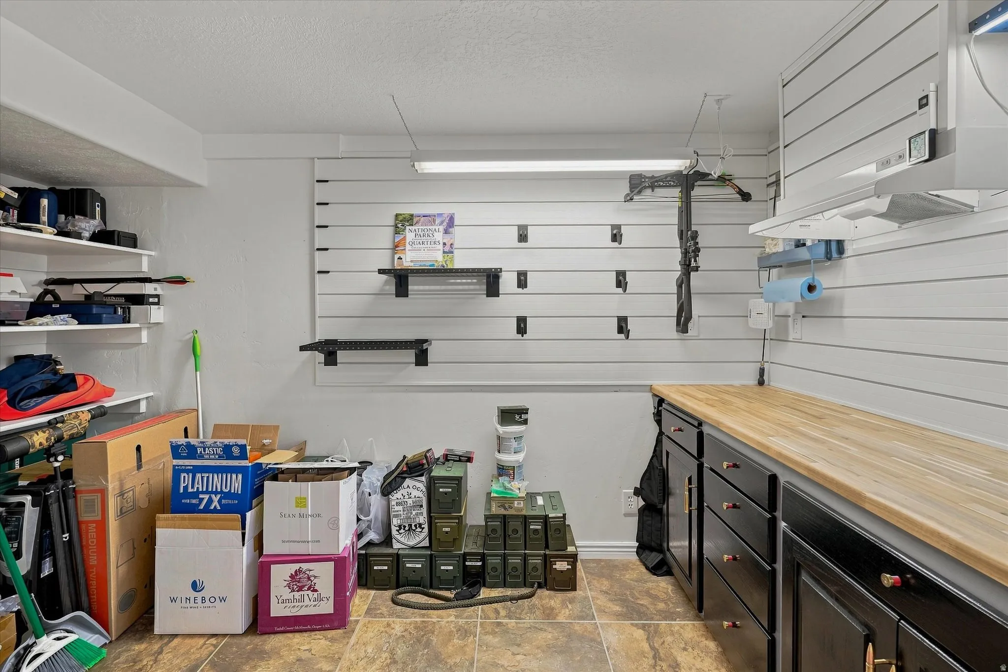 Integrated slat wall storage system, built-in cabinetry with wood-finish countertop, and recessed lighting