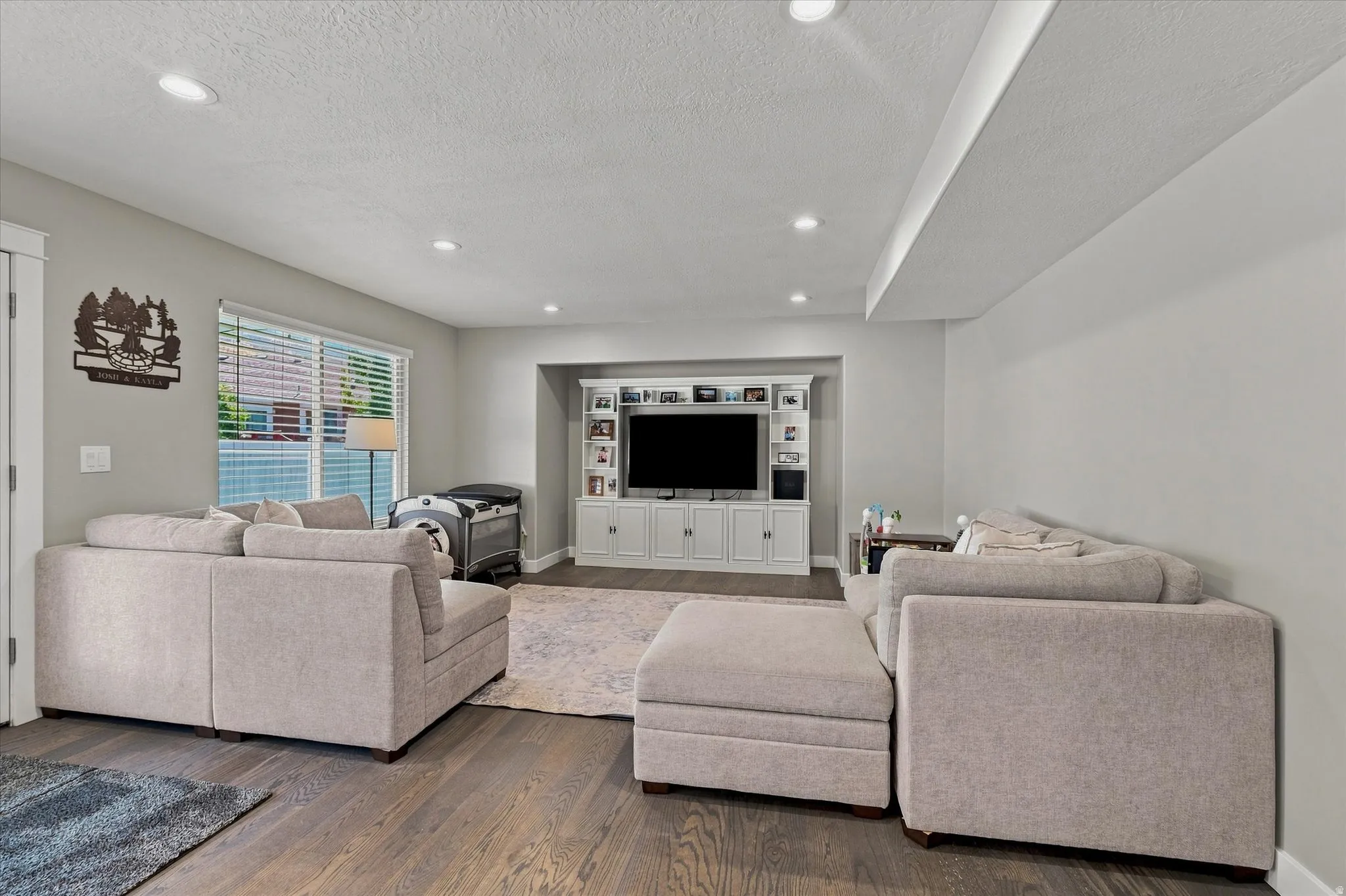 Recessed lighting, wood-finish flooring, and a built-in media center with shelving