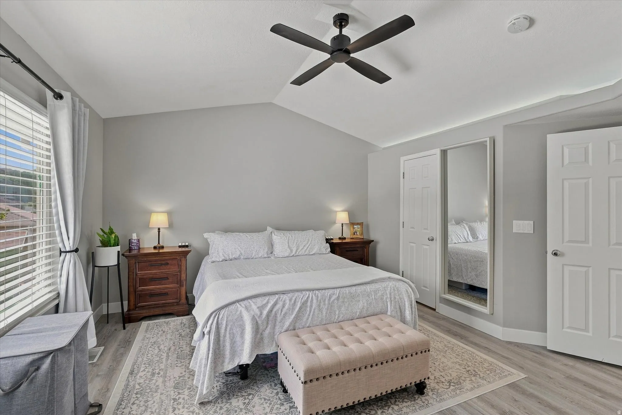 Vaulted ceiling with a ceiling fan, light wood-finish flooring, and white paneled doors