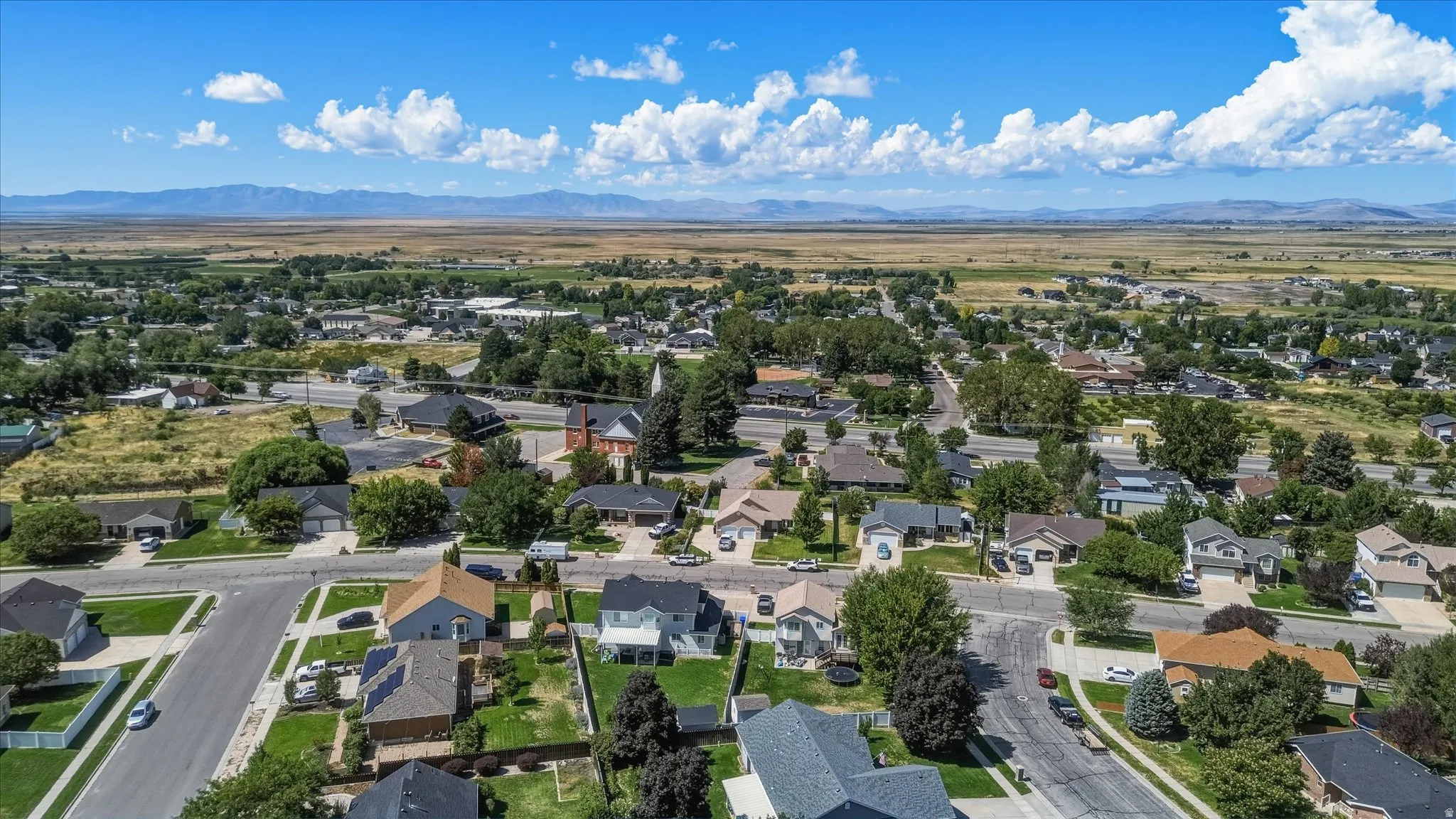 Residential neighborhood featuring paved streets, established landscaping, and distant mountain ranges