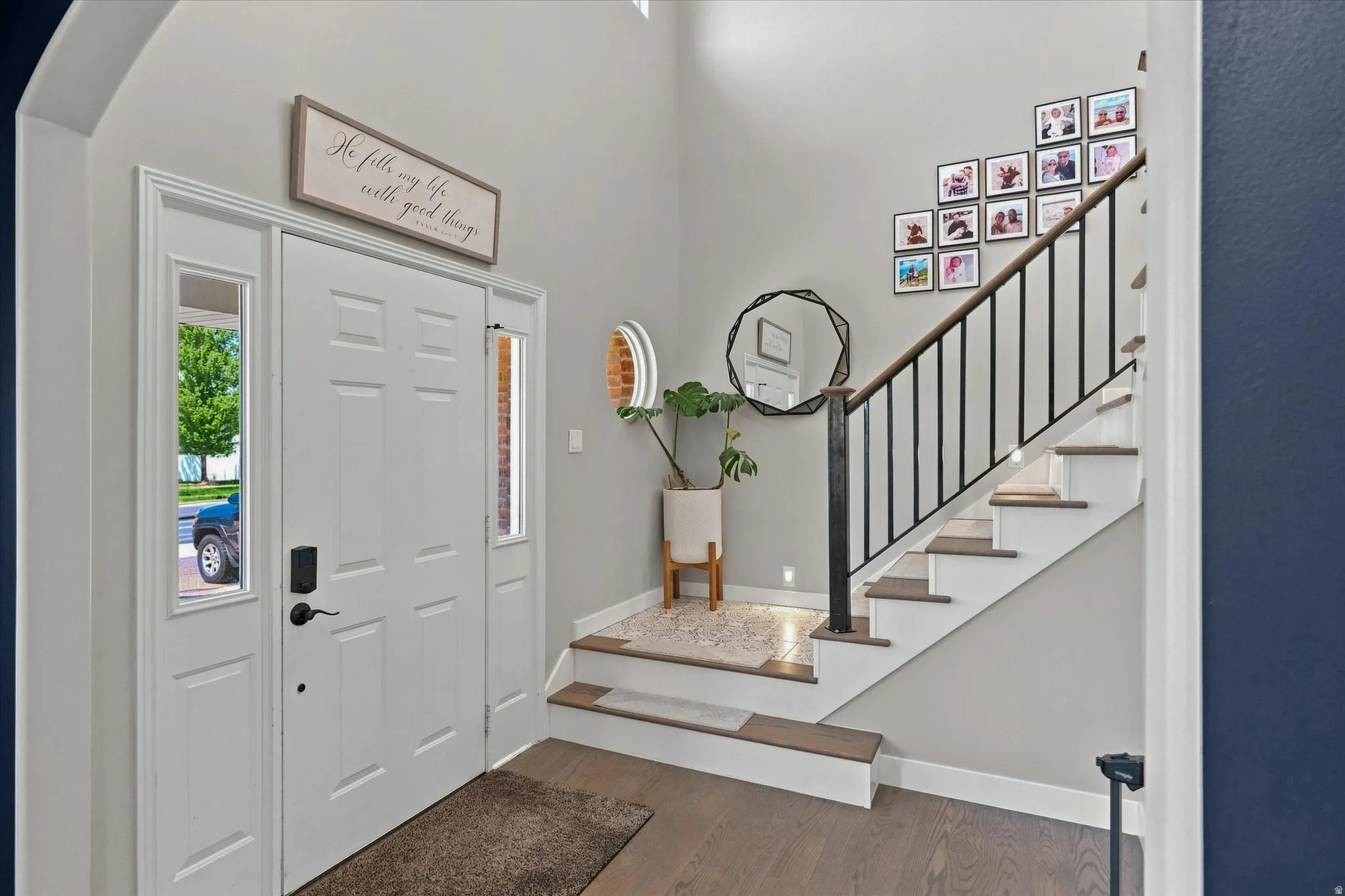 Entryway featuring a paneled door with sidelight windows, a staircase with wood-finish treads, and wrought iron balusters