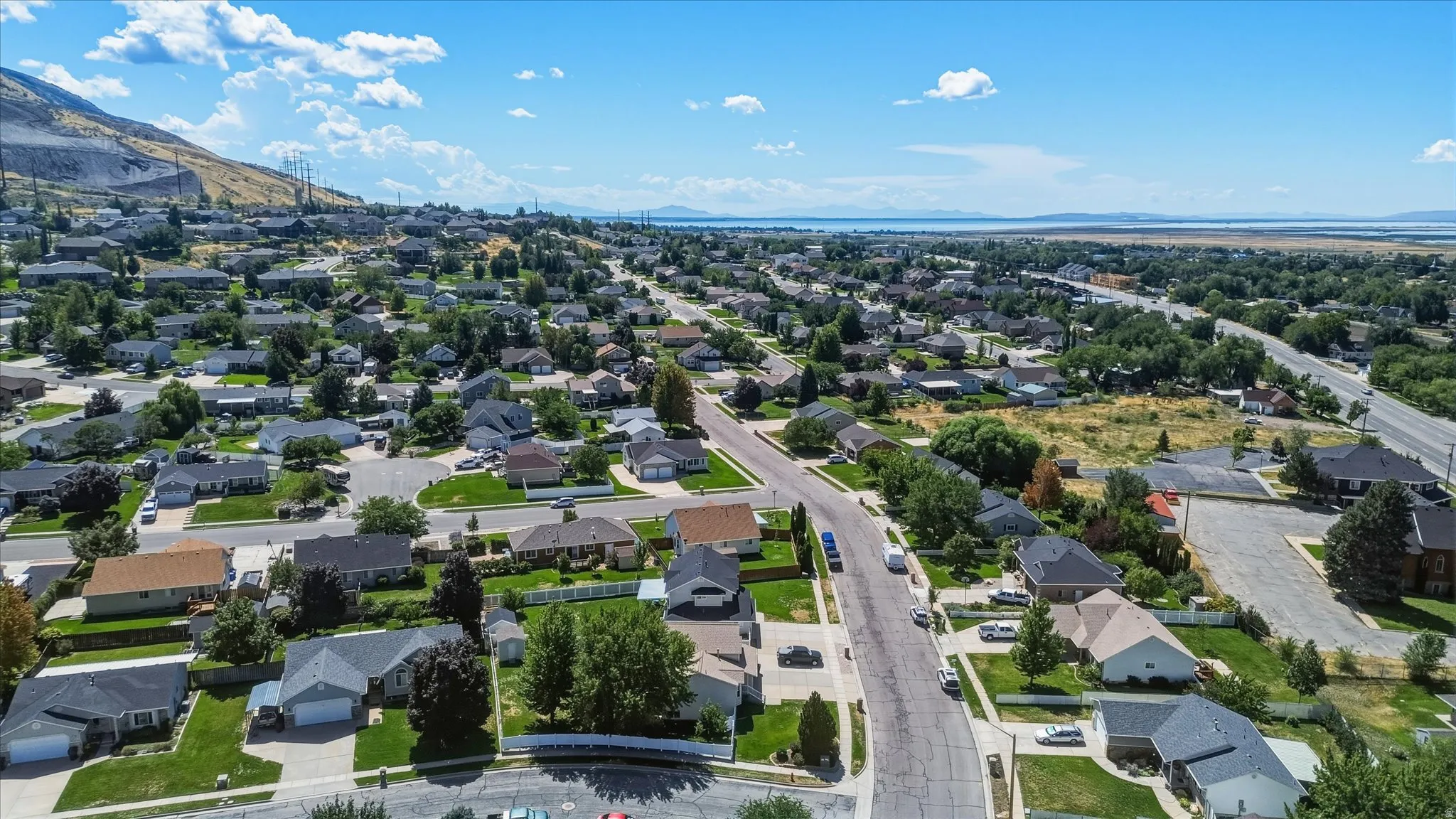 Residential neighborhood setting with established homes, paved streets, and a distant body of water