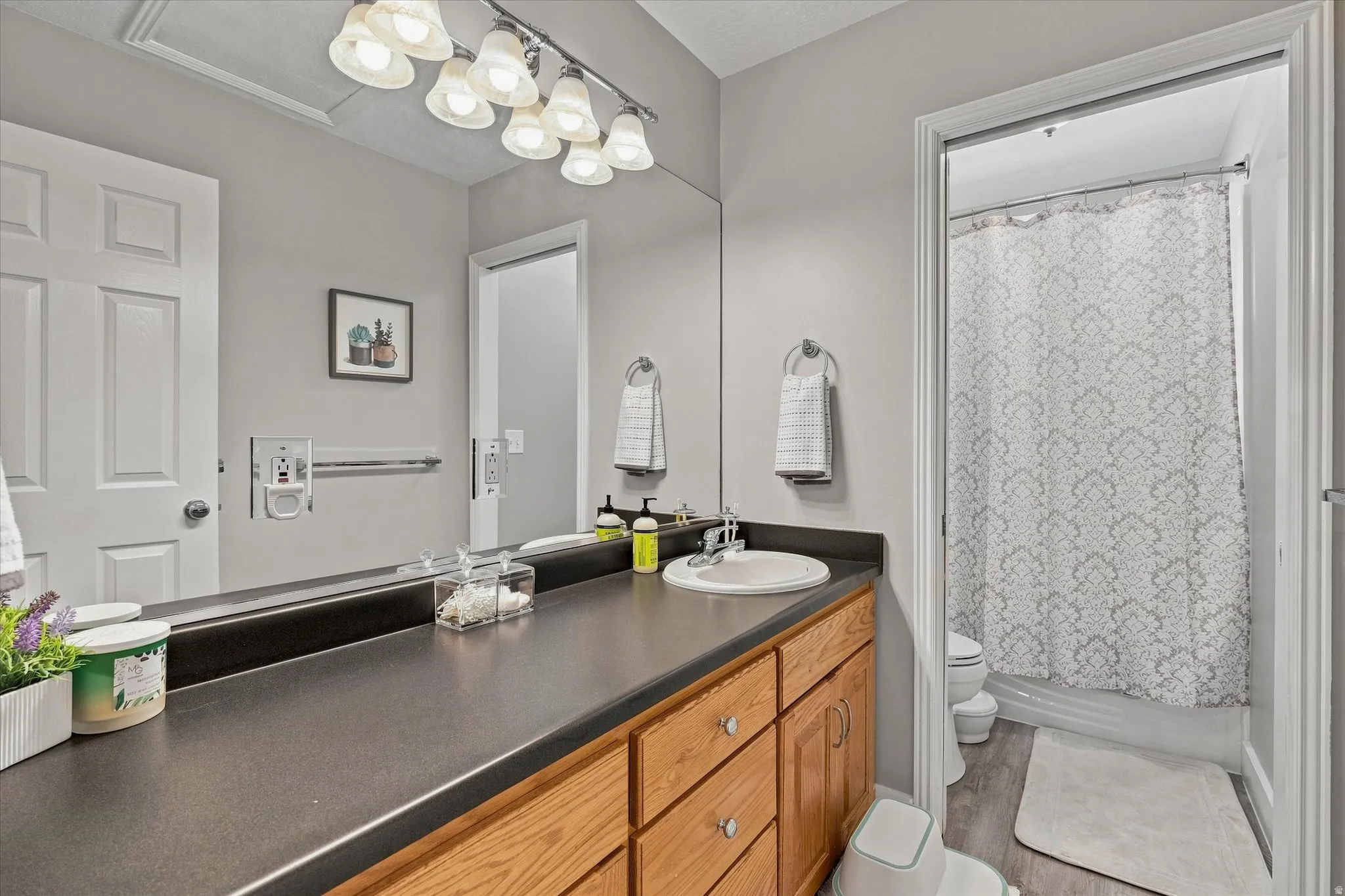Wood-finish cabinetry with a built-in vanity sink, dark countertop, and large wall mirror