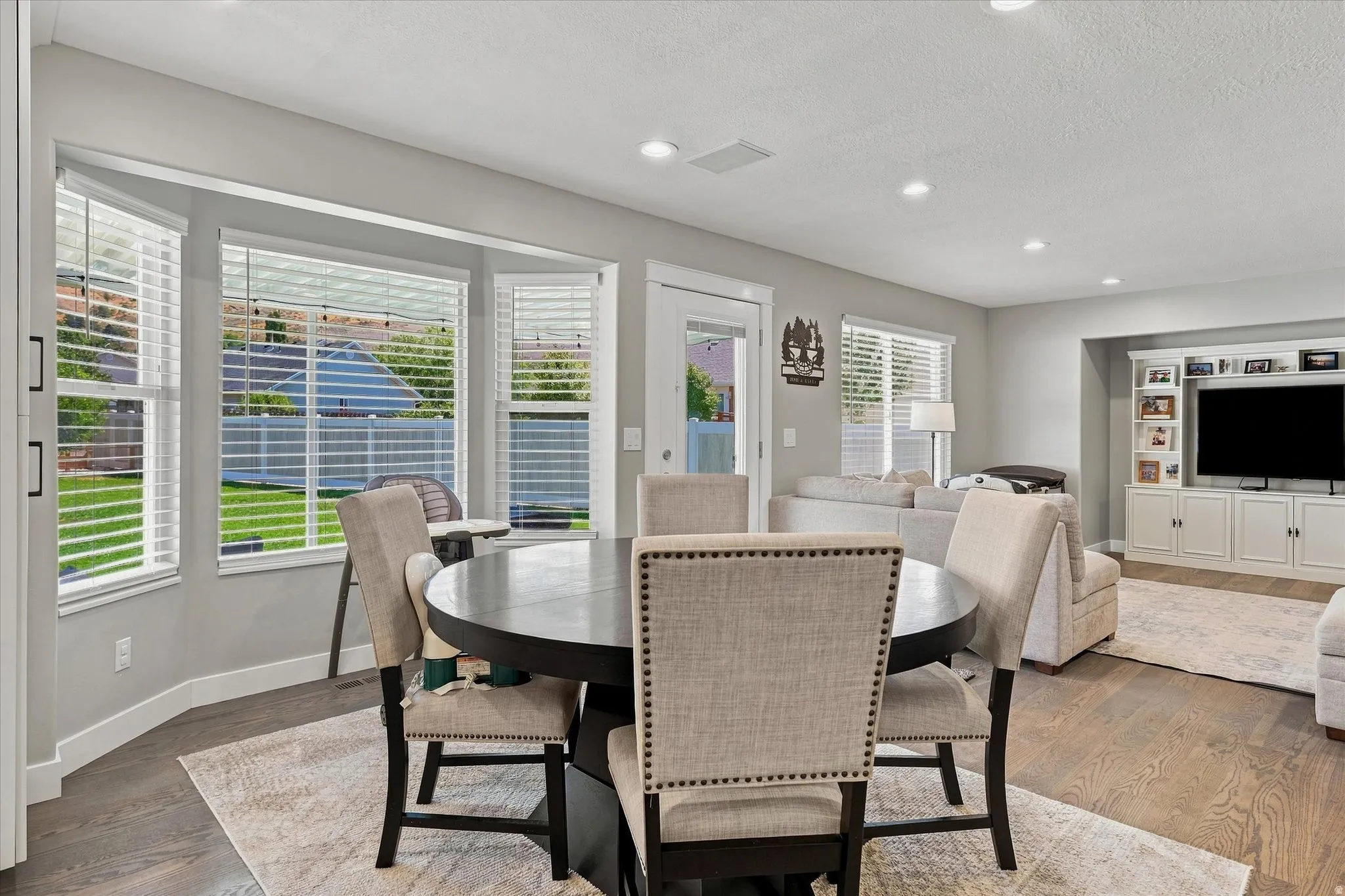Bay window with multiple panels, recessed lighting, built-in media cabinetry, wood-finish flooring, and a glass-paneled exterior door