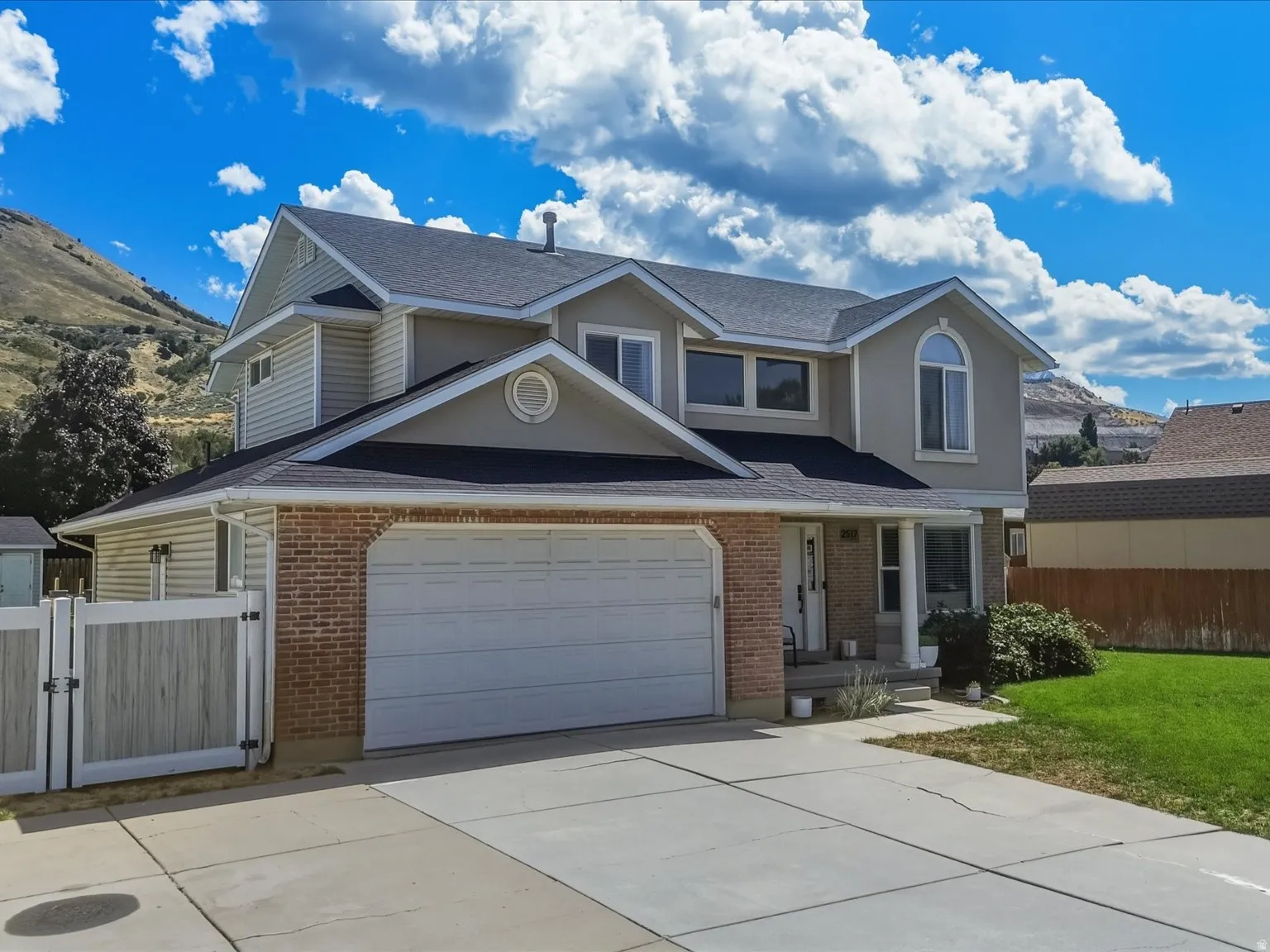 Multi-level exterior with brick and siding facade, two-car garage, and a concrete driveway