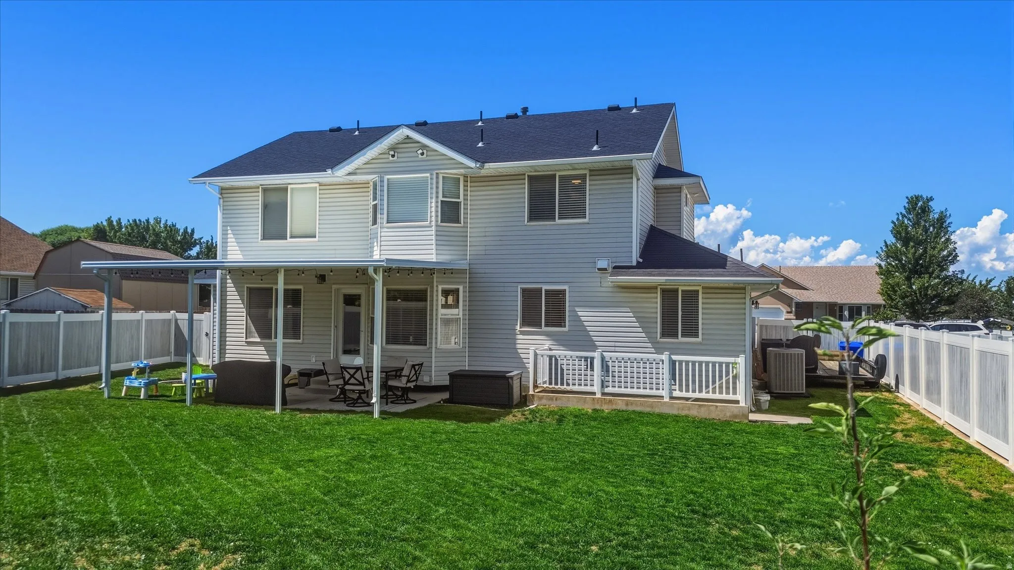 Expansive backyard featuring a covered patio, a privacy fence, and a manicured lawn