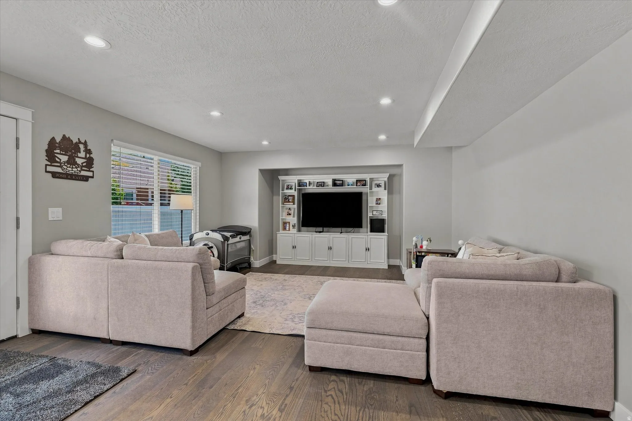 Wood-finish flooring, recessed lighting, and a built-in media center with display shelving