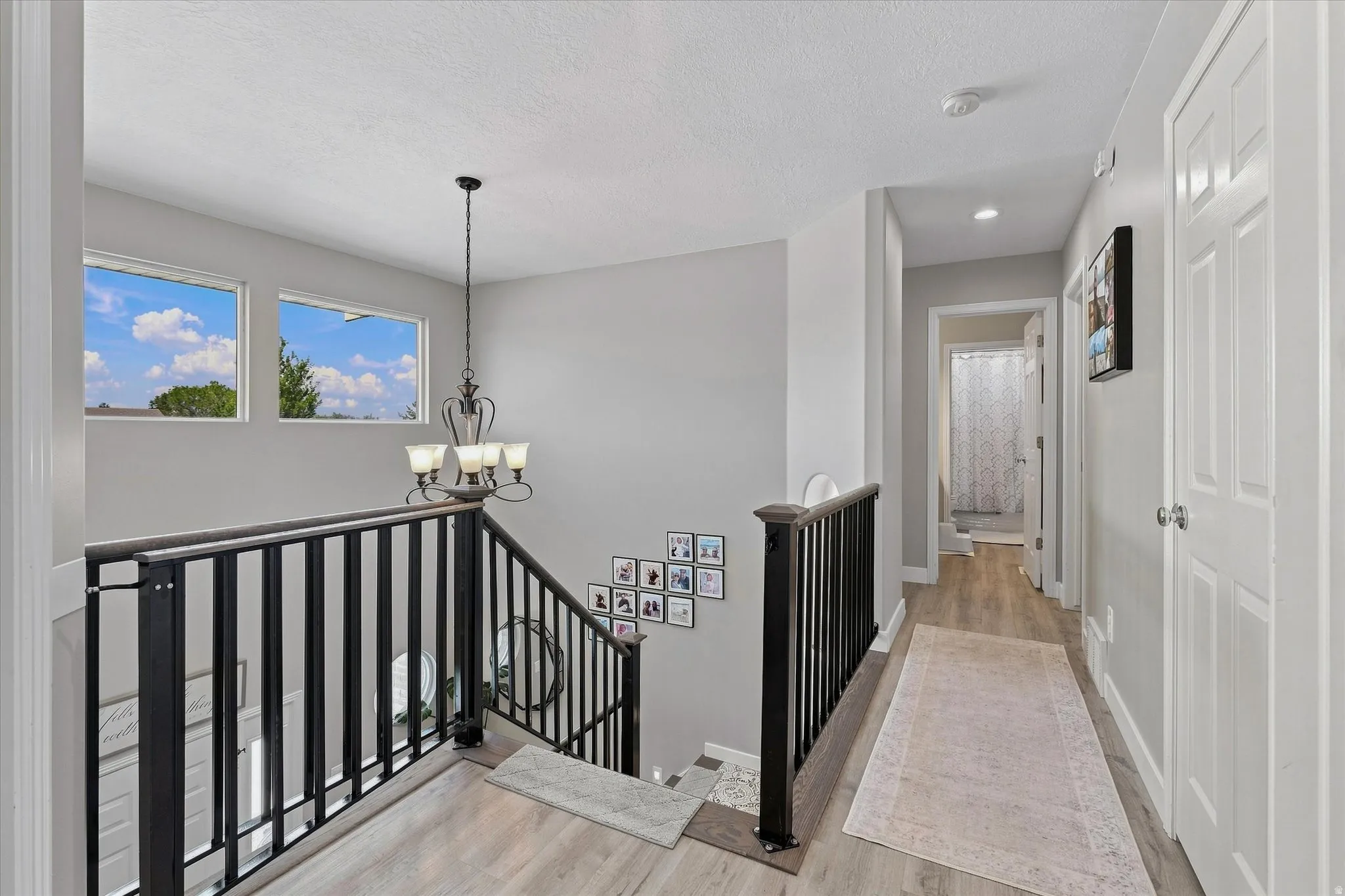 Upper level hallway featuring wood-finish flooring, white paneled doors, recessed lighting, and a chandelier