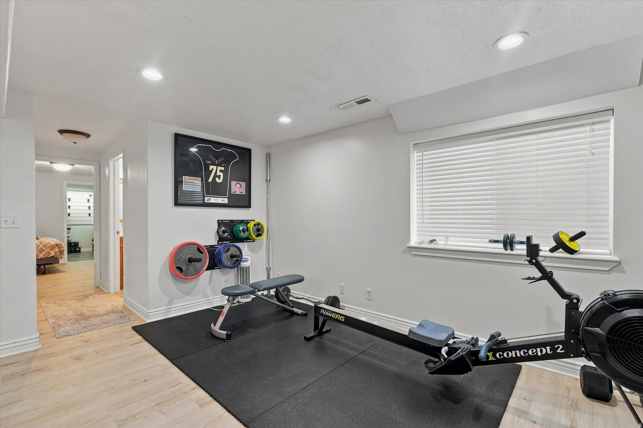 Recessed lighting, light-toned wood-finish flooring, a window with blinds, and white painted walls