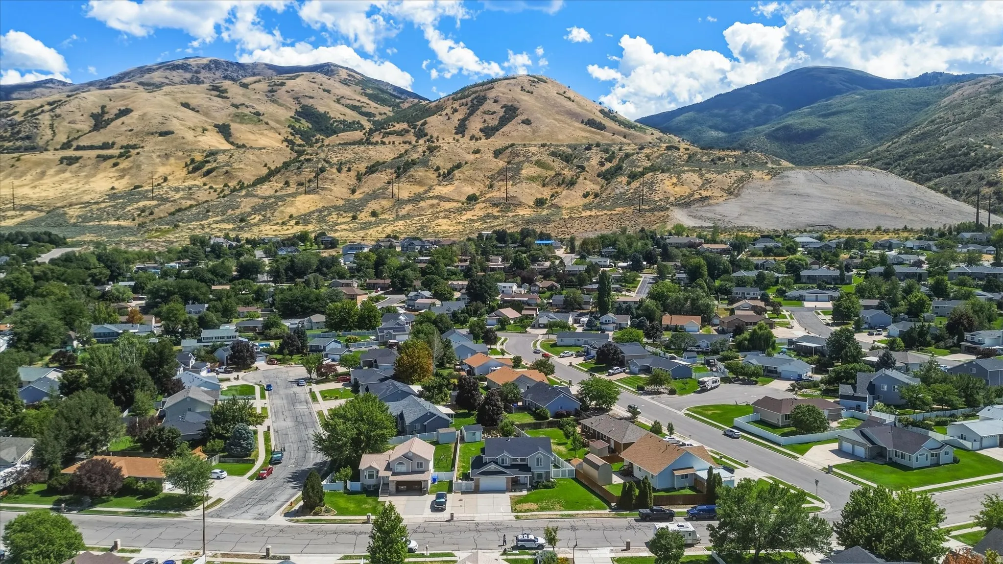 Residential neighborhood with established streets and mature trees, set against a backdrop of mountain terrain