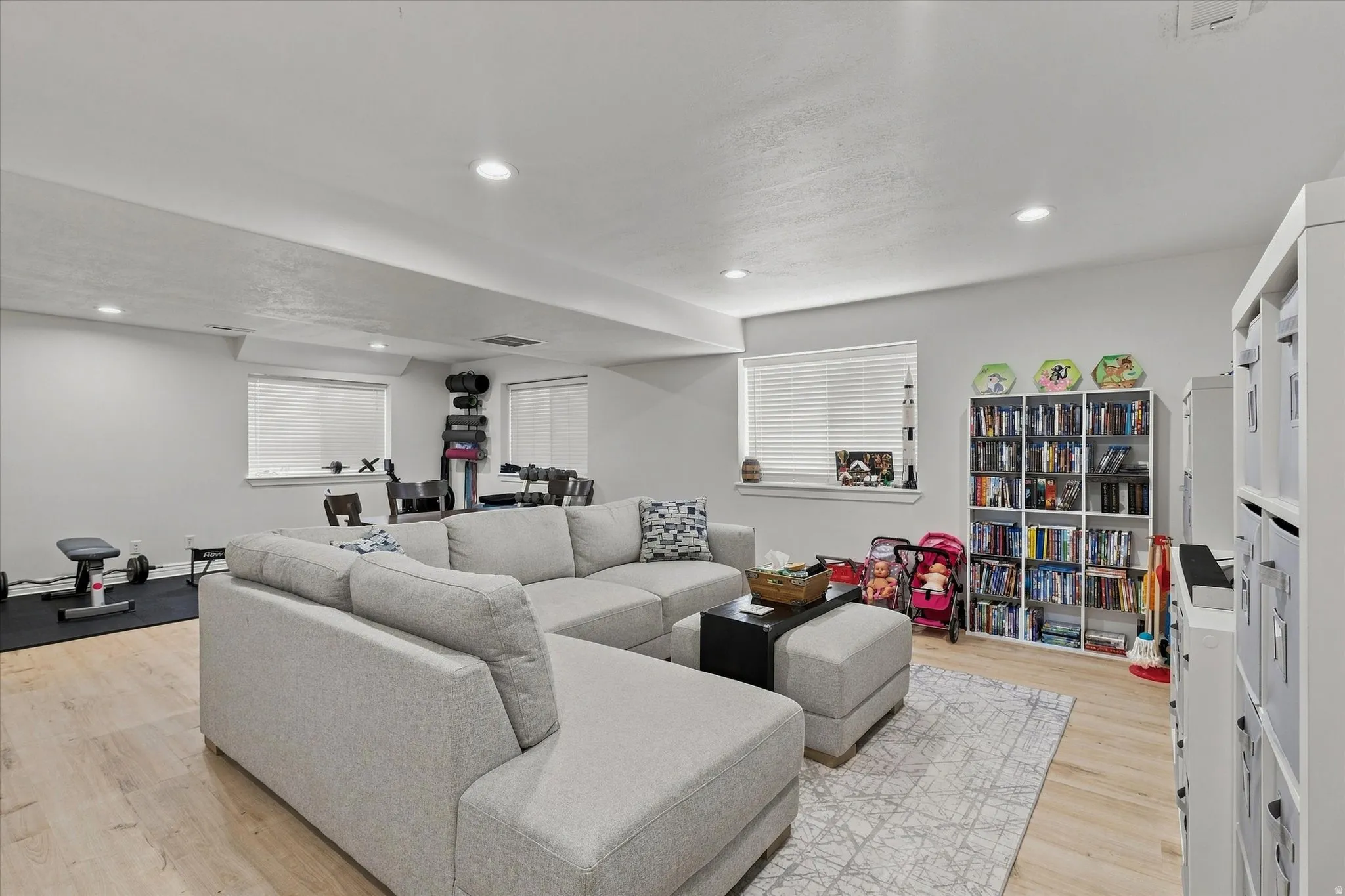 Recessed lighting, wood-finish flooring, multiple windows with blinds, and built-in shelving