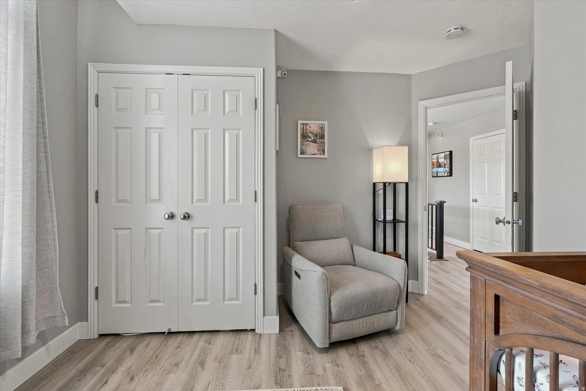 Wood-finish flooring, paneled bifold closet doors with satin nickel hardware, and light gray wall paint
