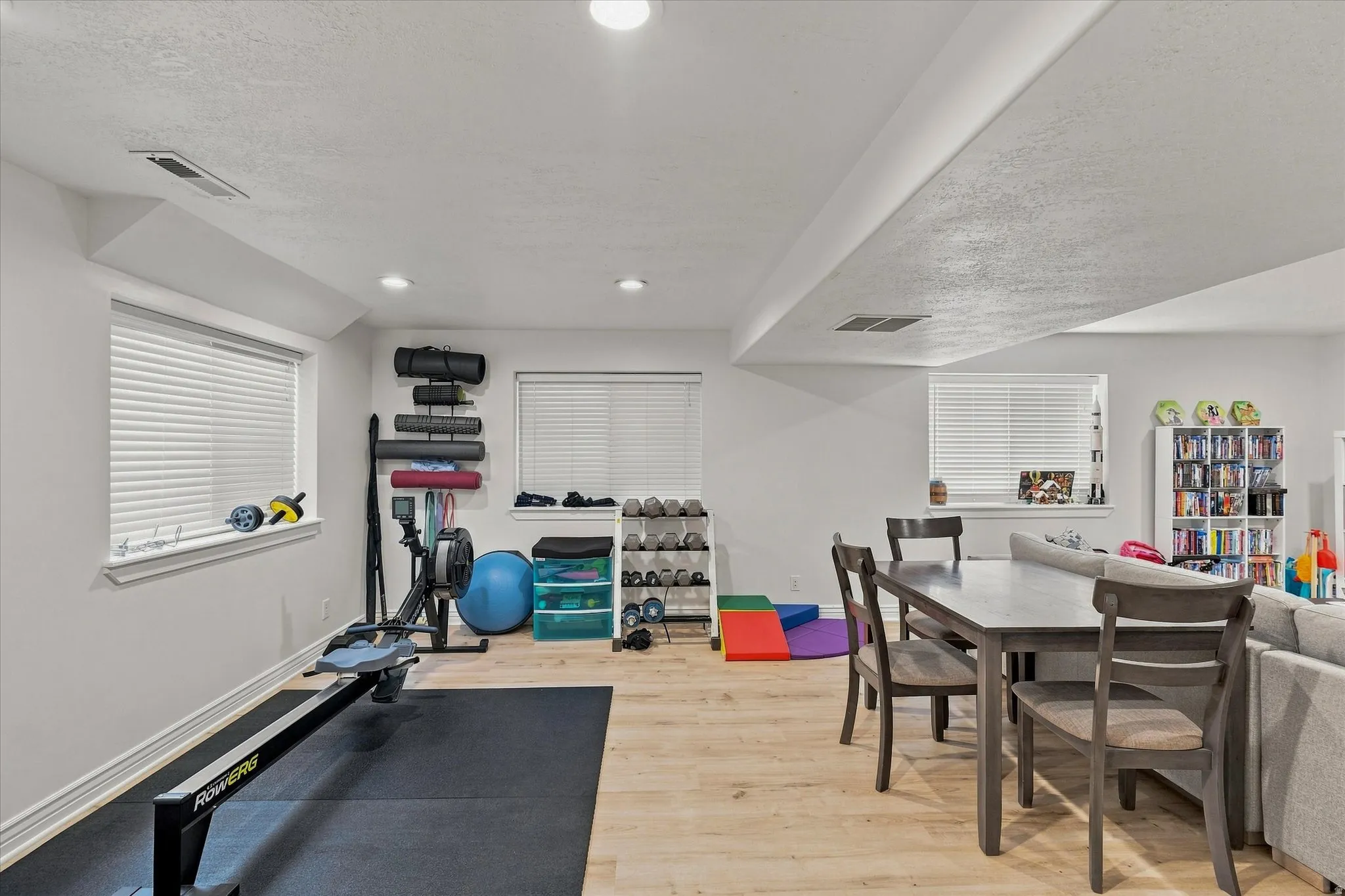 Recessed lighting, light wood-finish flooring, and white walls with multiple windows