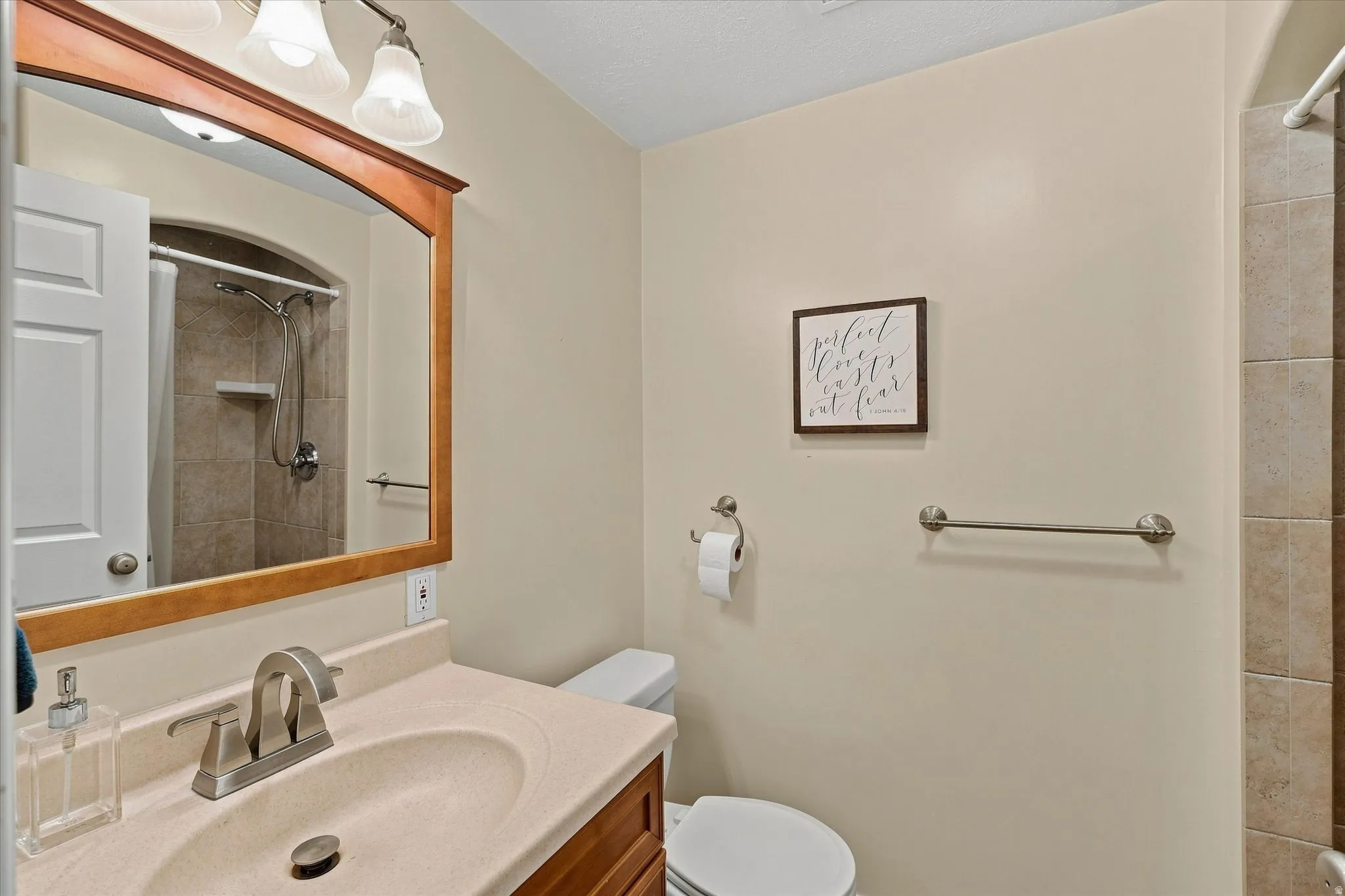 Vanity with integrated sink, wood-finish cabinetry, brushed nickel faucet, and framed mirror