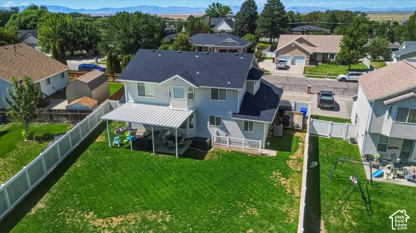 Expansive green lawn, white privacy fencing, covered patio structure, rear deck, and a shed