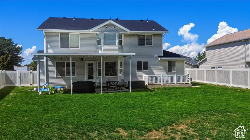Expansive green lawn with a full vinyl fence and a covered patio