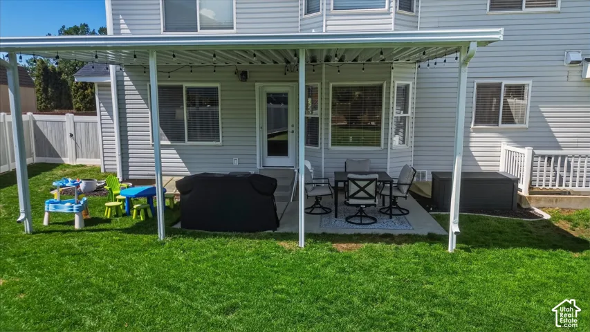 Lush green lawn with a covered patio featuring string lights