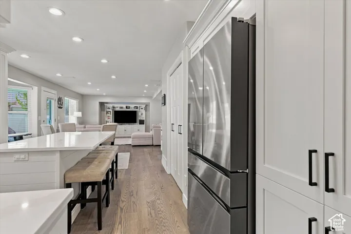 Open-concept living space featuring wood-finish flooring, recessed lighting, and a kitchen island with a light-toned countertop