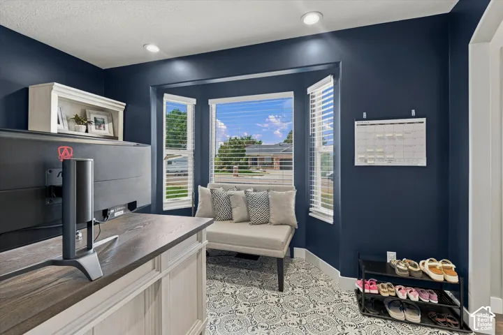 Recessed lighting illuminates the room, featuring a bay window with blinds