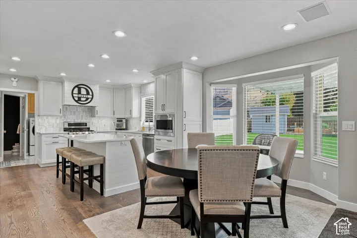 Kitchen featuring light cabinetry, a central island with countertop seating, stainless steel appliances, and wood-finish flooring
