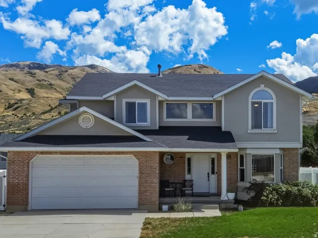 Two-story residence featuring a brick and stucco exterior, an attached two-car garage, and a paved driveway