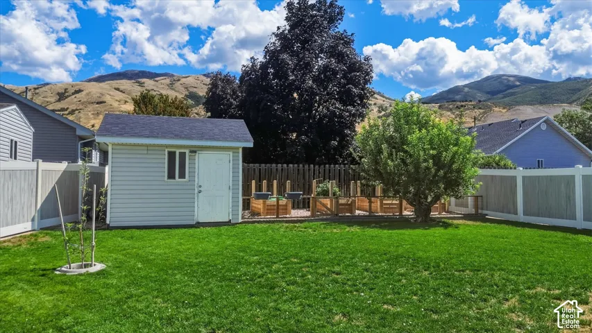 Expansive lawn area with a detached storage shed, raised garden beds, and mature trees