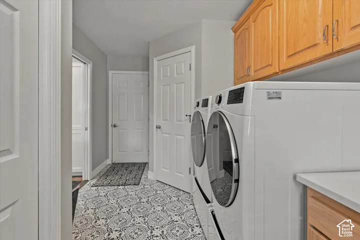 Laundry area featuring patterned tile flooring, wood cabinetry, and a countertop surface