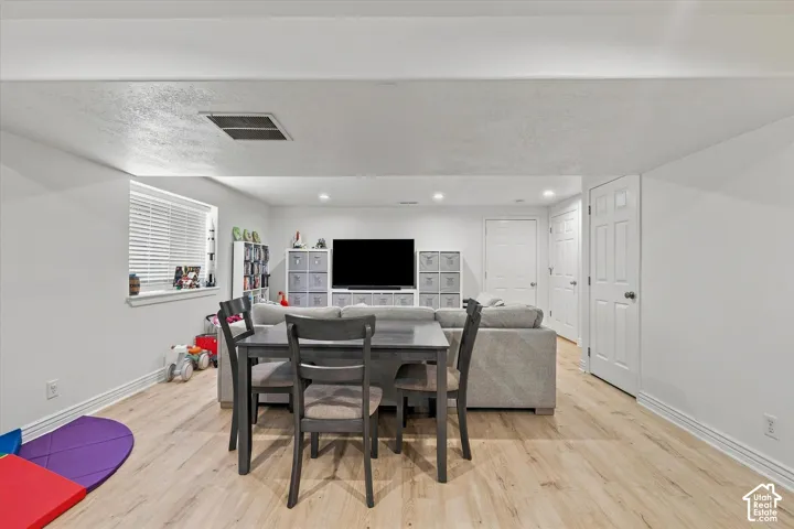 Recessed lighting, light wood-finish flooring, white paneled doors, and a window with blinds