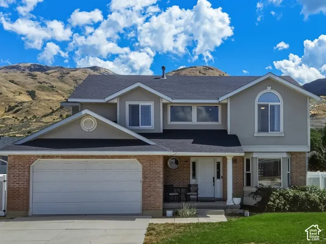 Two-story residence featuring a brick and stucco exterior, an attached two-car garage, and a paved driveway