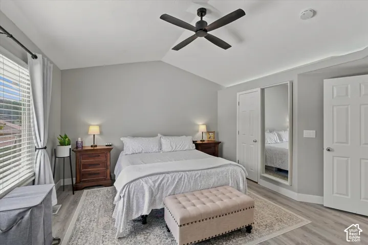 Vaulted ceiling with a ceiling fan, light wood-finish flooring, and white paneled doors