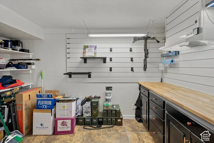 Integrated slat wall storage system, built-in cabinetry with wood-finish countertop, and recessed lighting