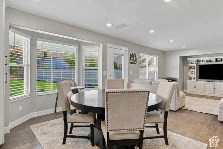 Bay window with multiple panels, recessed lighting, built-in media cabinetry, wood-finish flooring, and a glass-paneled exterior door