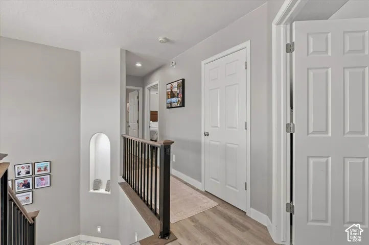 Upper landing with wood-finish flooring, recessed lighting, white paneled doors, and a built-in arched wall niche