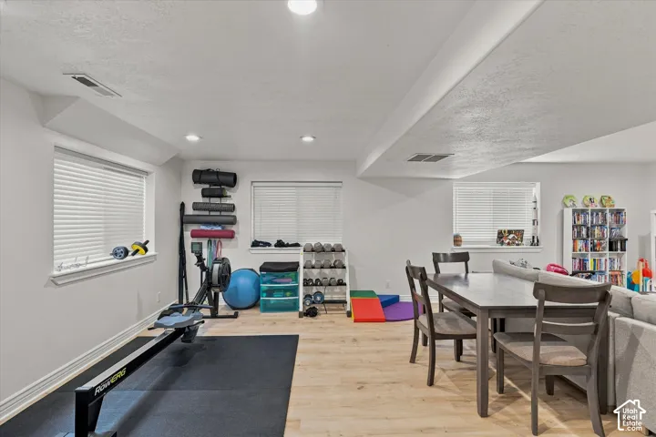 Recessed lighting, light wood-finish flooring, and white walls with multiple windows