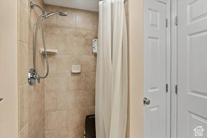 Tiled shower with handheld shower fixture and built-in shelving