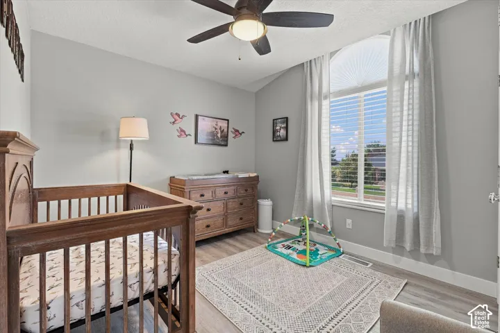 Vaulted ceiling with a ceiling fan, arched window with blinds, and wood-finish flooring