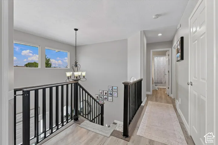 Upper level hallway featuring wood-finish flooring, white paneled doors, recessed lighting, and a chandelier