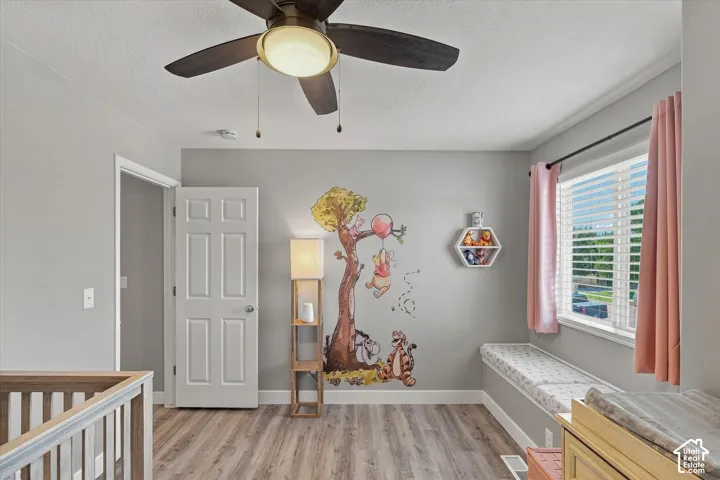 Wood-finish flooring, ceiling fan, natural light from a window with blinds, and a built-in window seat