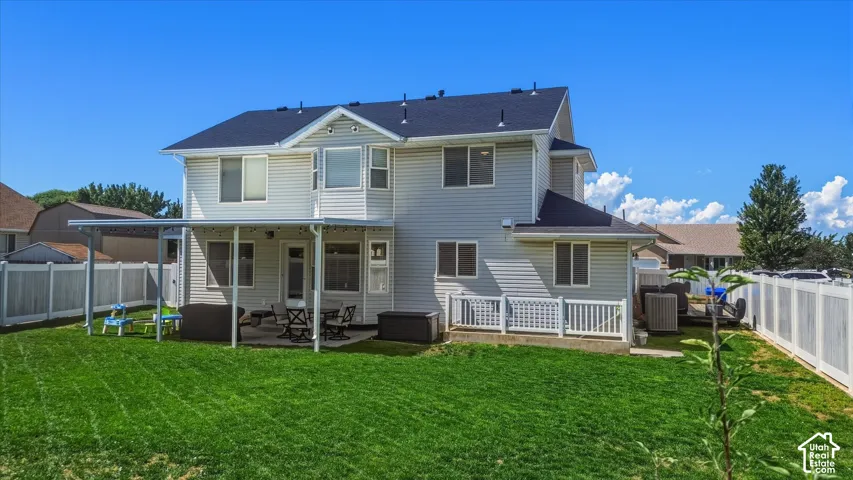 Expansive backyard featuring a covered patio, a privacy fence, and a manicured lawn
