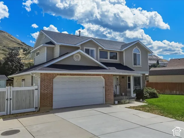 Multi-level exterior with brick and siding facade, two-car garage, and a concrete driveway