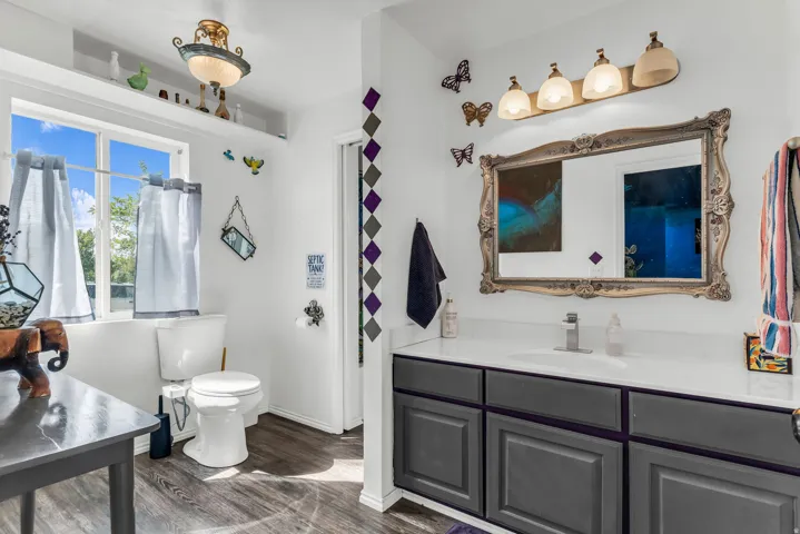White vanity with a single basin, stainless steel faucet, and an ornate framed mirror