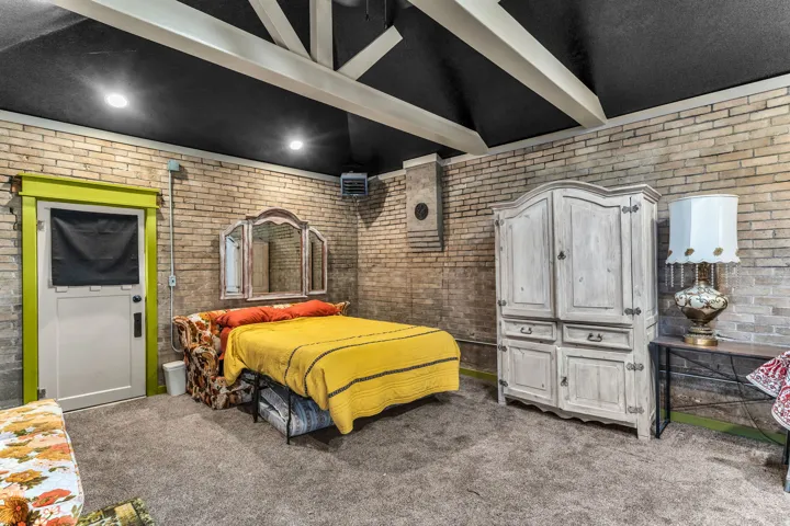 Exposed brick walls, vaulted ceiling with exposed beams, recessed lighting, and carpet flooring