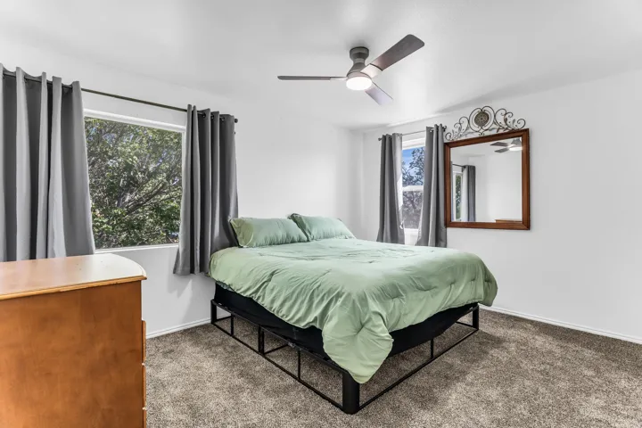 Ceiling fan with integrated lighting, two windows, wall-to-wall carpeting, and bright white walls
