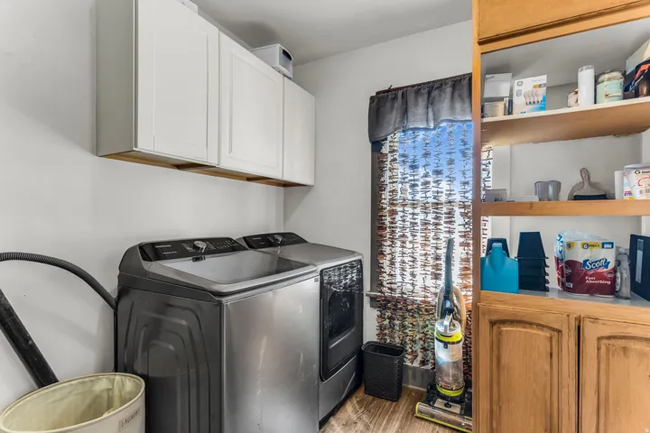 White upper cabinetry, wood-finish flooring, and built-in wood shelving