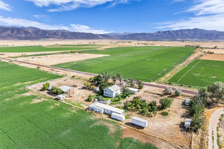 Expansive agricultural property featuring multiple cultivated fields, a detached house, and several outbuildings