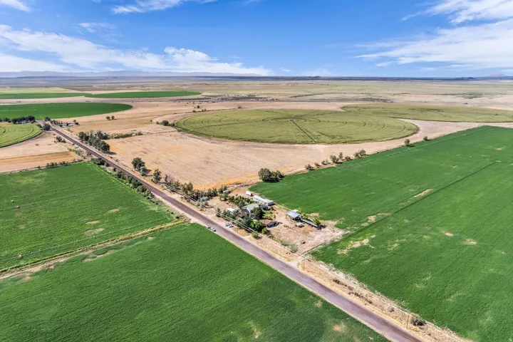 Expansive acreage featuring cultivated fields, a rural road, and distant mountain ranges