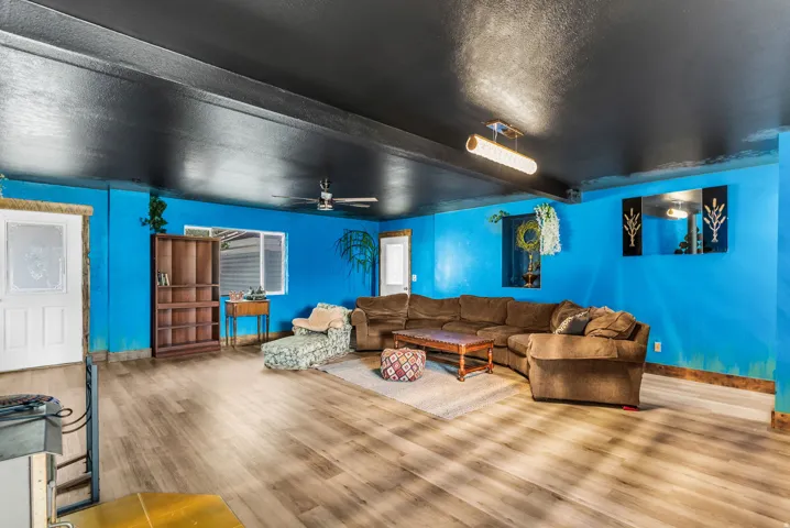 Wood-finish flooring throughout, complemented by a ceiling fan and a rectangular contemporary light fixture